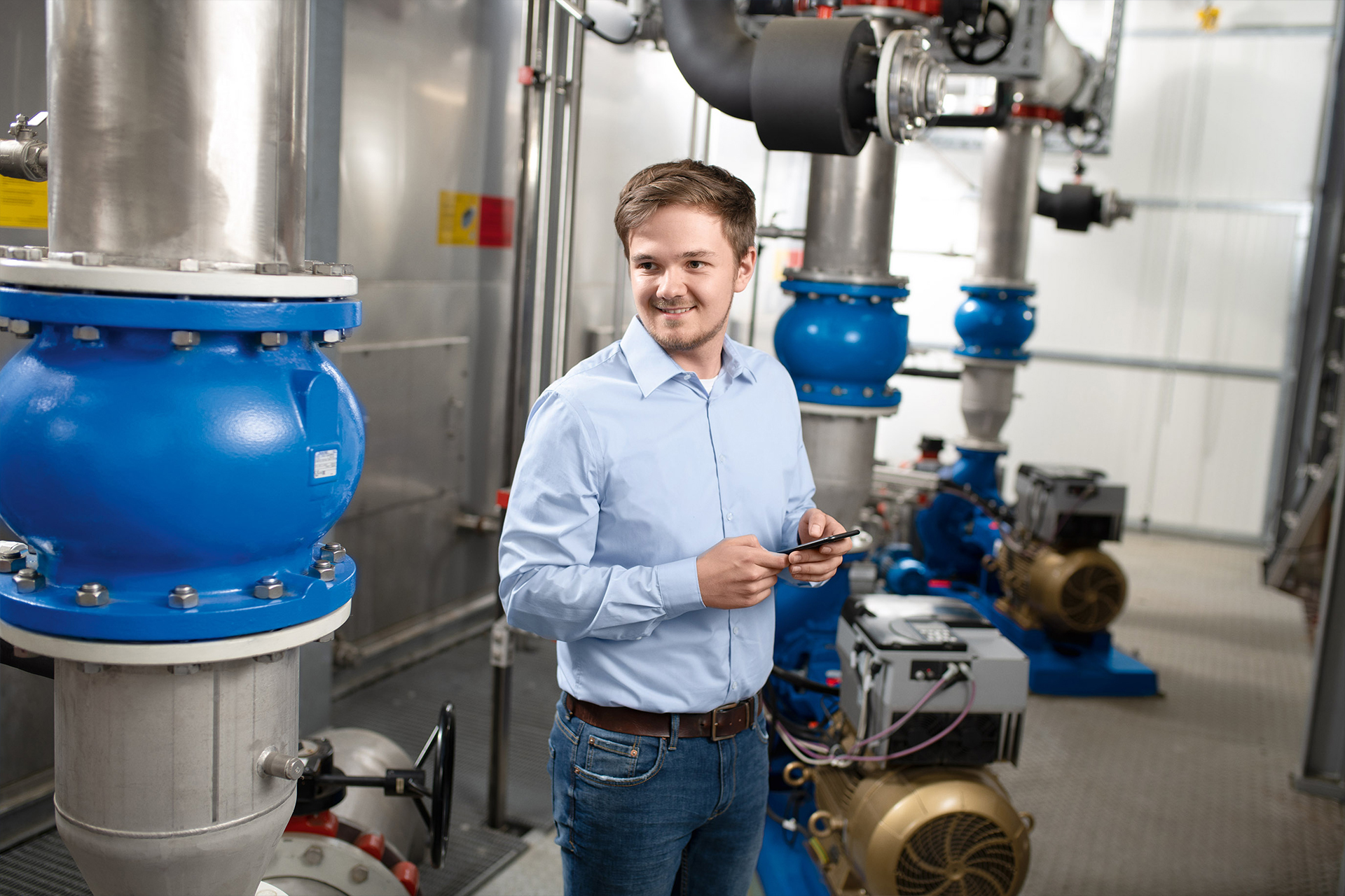 A system operator standing next to his pumps with a smartphone